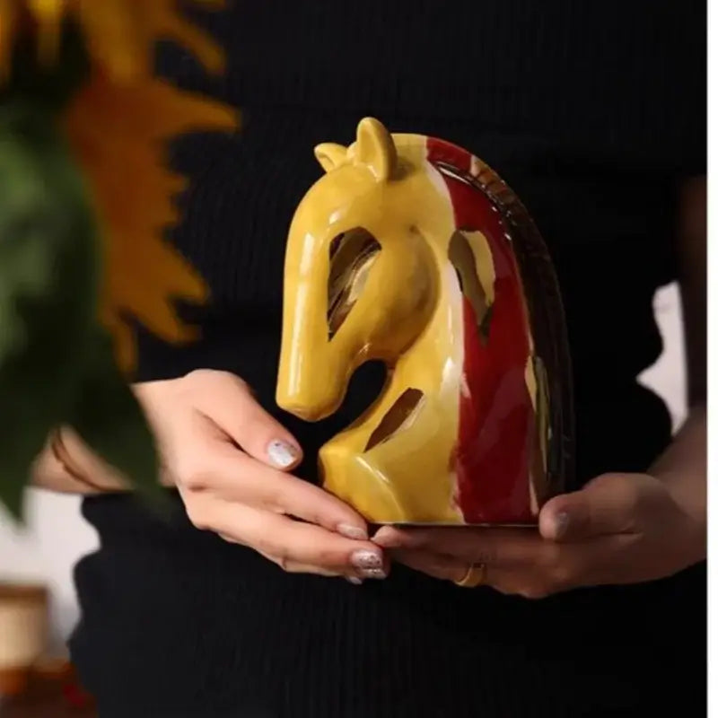 Glossy ceramic geometric horse head bookend in vibrant red and yellow with cut-out eyes and mane details for decor