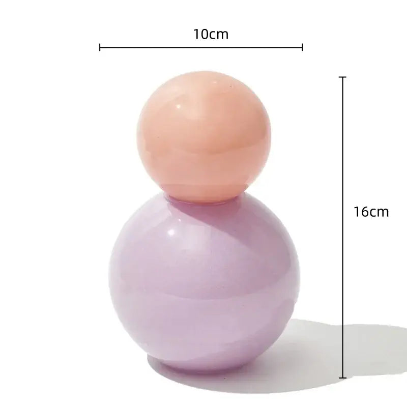 A geometric sphere glass vase with lid featuring a glossy lavender base and smooth peach top for desktop storage