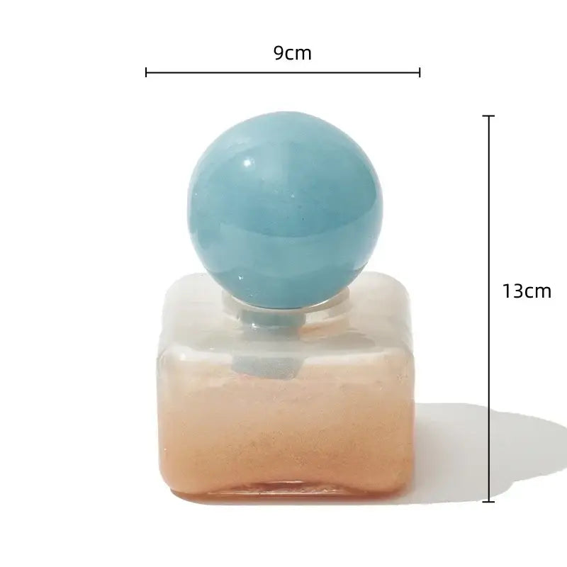 Translucent geometric sphere glass vase with lid featuring a peach-to-clear body and light blue spherical cap for desktop storage