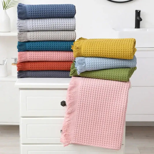 Stack of colorful multi colored geometric tassel bath towels with waffle weave and fringed edges for bathroom decor