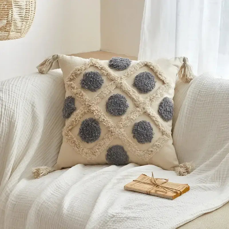 Beige cushion cover with gray pom-pom accents and geometric tufted tassel design for living room decor