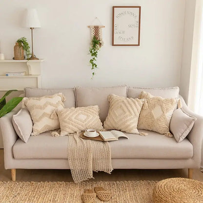 Beige upholstered sofa with decorbites geometric tufted tassel pillowcases in cotton linen and a woven blanket draped