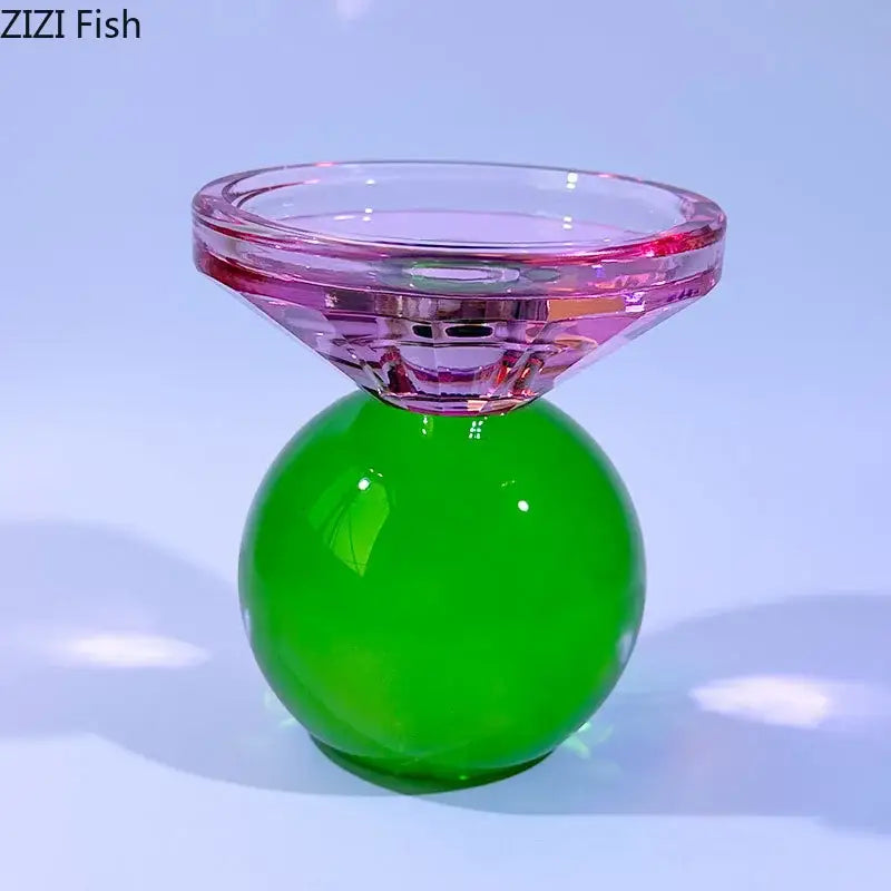 A vibrant crystal candle holder with a faceted pink top and glossy green spherical base for dining room use