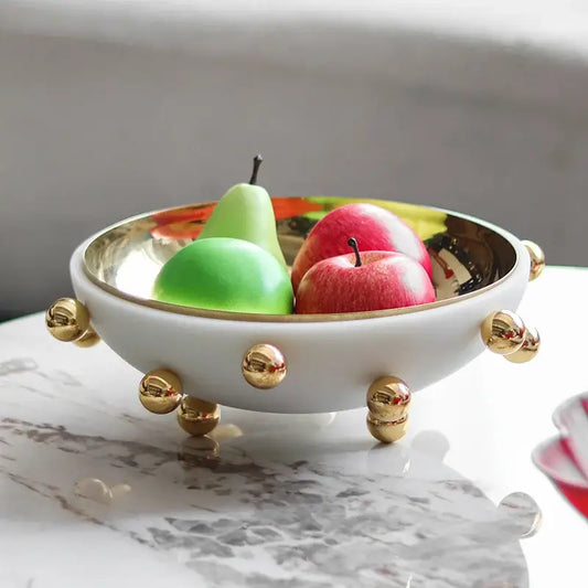 Geometric white and gold ceramic fruit bowl round with metallic accents and decorative spherical feet for kitchen use