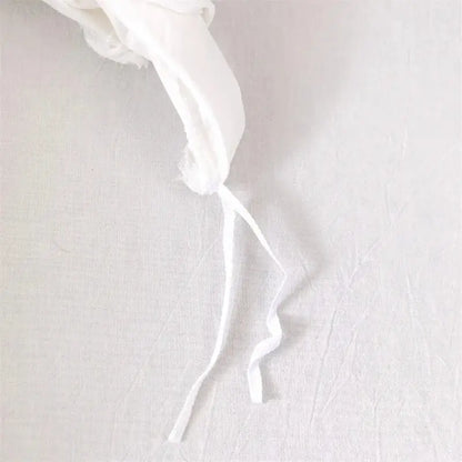 Delicate white fabric ribbon with frayed edge on geometric white quilted duvet cover set for bedroom bedding