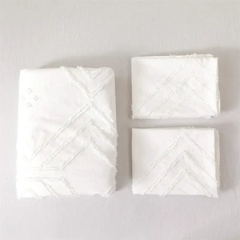 White embroidered handkerchiefs with textured chevron pattern featured on geometric white quilted duvet cover set