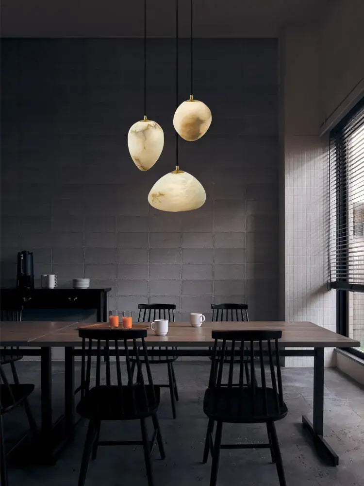 Three creamy white marble pendant lights with organic shades hang from black cords in decorbites geometry marble led chandelier