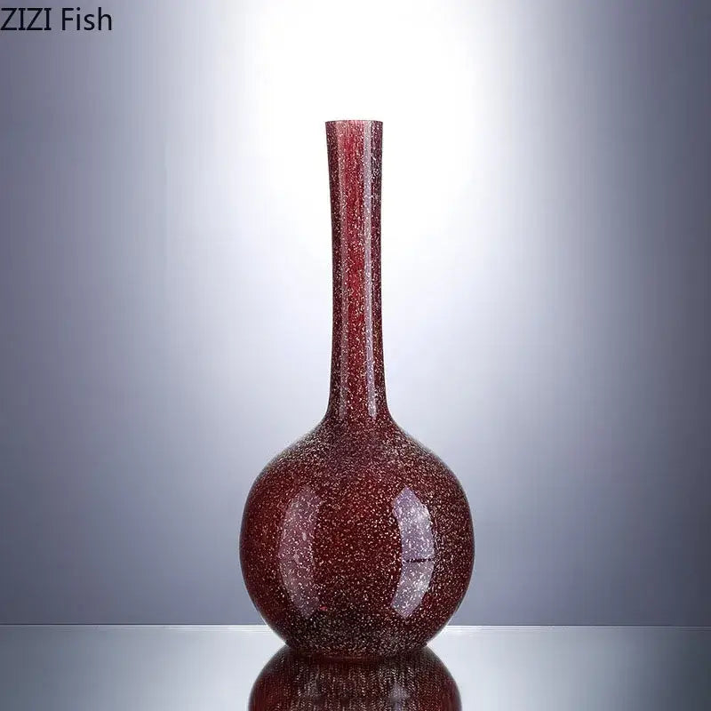 A sleek gilded red glass vase with speckled texture and slender neck holding artificial flowers for decorbites decor