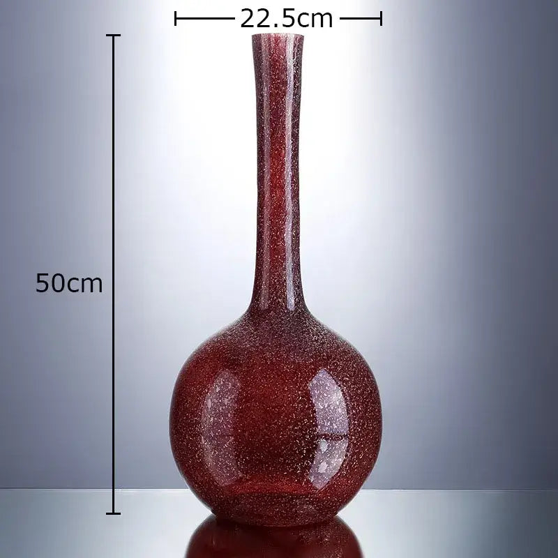 A tall slender gilded red glass vase with speckled texture and bulbous base holding artificial flowers decorbites gilded red desk decor