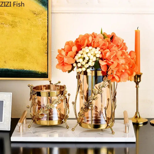 Gold-toned gilded tree branch glass vase with intricate leaf detailing holding orange hydrangeas and white berries