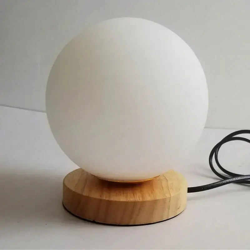 A sleek matte white glass ball table lamp with a natural wooden base perfect for bedroom night light decorbites glass ball