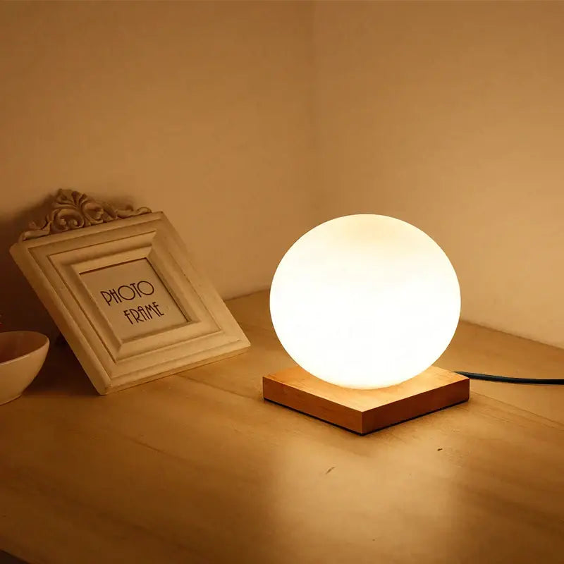 Glass ball led table lamp with warm white matte finish resting on wooden base for bedroom night light decorbites glass ball