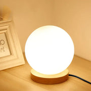 A warm glowing glass ball led table lamp with matte white finish and wooden base for bedroom night light decorbites glass ball