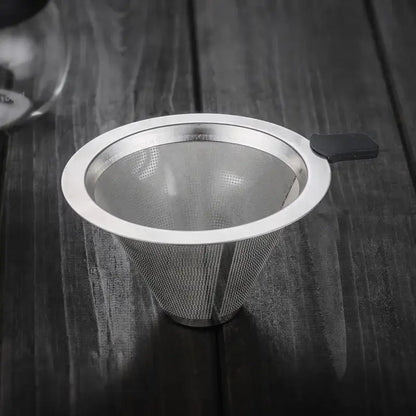 A sleek conical stainless steel filter with black handle for use in a glass coffee pot pour over kitchen carafe