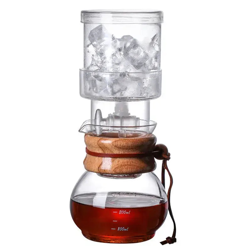 Clear glass cold brew coffee maker with wooden accents and brown leather strap for brewing cold brew coffee