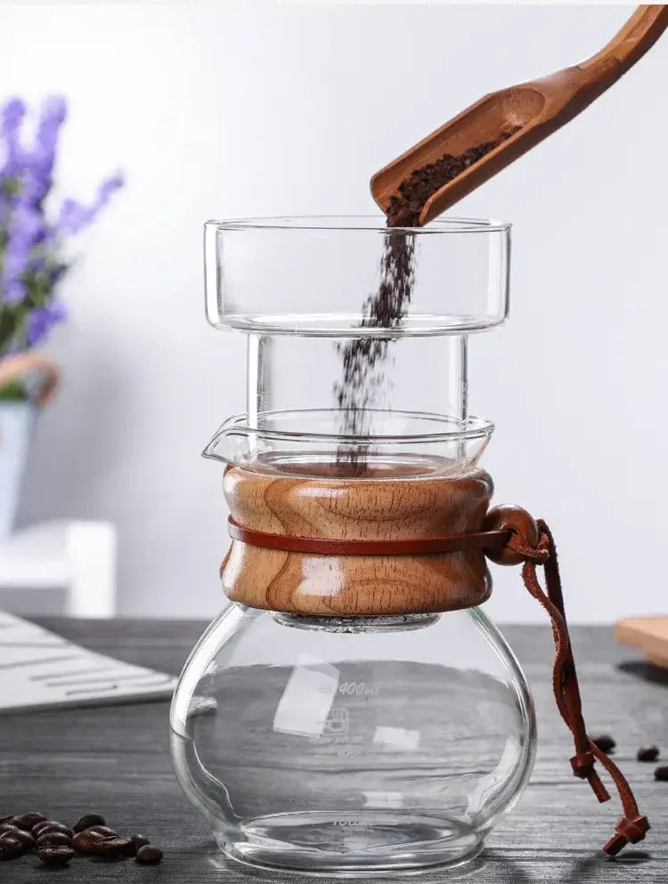 Clear glass cold brew coffee maker with warm wooden lid handle and leather strap for secure brew coffee use