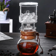 Clear glass cold brew coffee maker with wooden accents and brown leather strap for brewing cold brew coffee