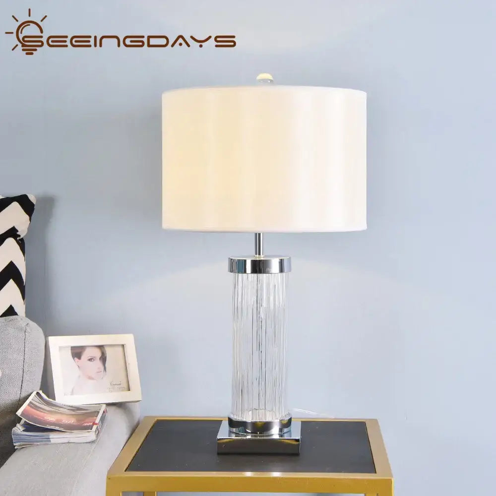 Clear glass crystal cylinder table lamp with chrome base and cream fabric shade for bedroom use