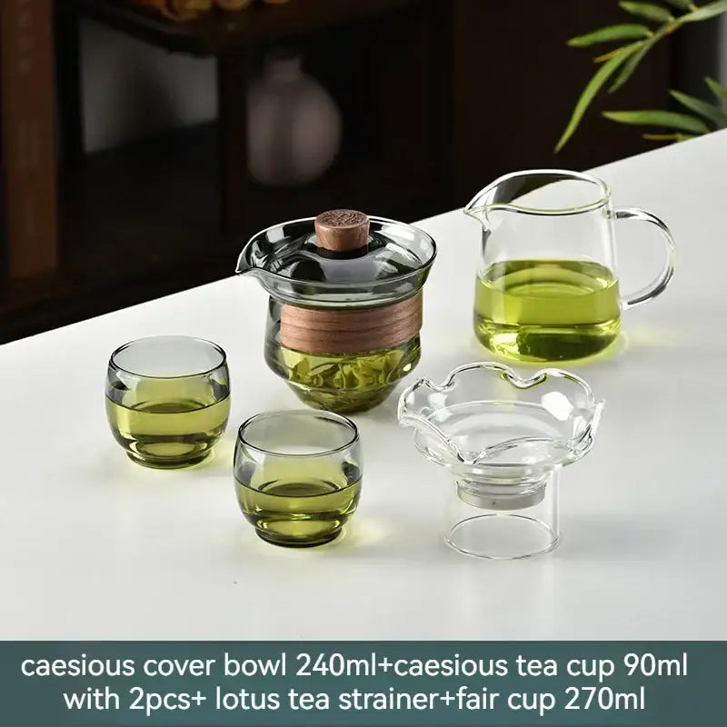 Glass gaiwan cup set with clear glass teapot, wooden lid, copper band, lotus-shaped strainer, and green-tinted cups