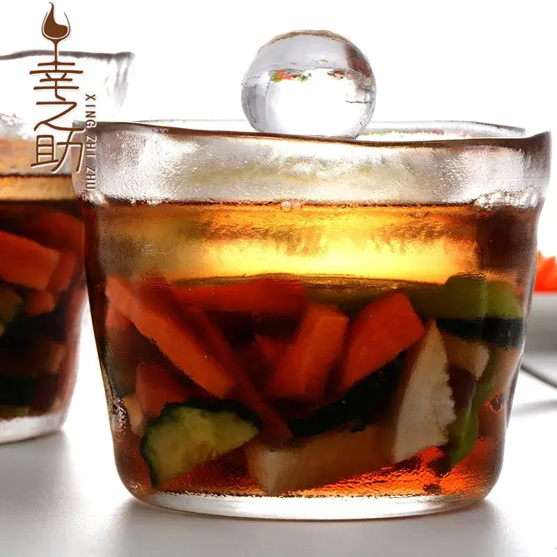 Clear glass storage jar with textured rim and spherical ice ball lid filled with colorful pickled vegetables for glass kimchi storage