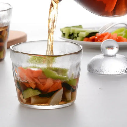 Clear glass decorbites glass kimchi storage jar with textured lid filled with colorful vegetables and dark amber liquid