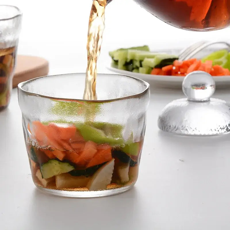 Clear glass decorbites glass kimchi storage jar with textured lid filled with colorful vegetables and dark amber liquid