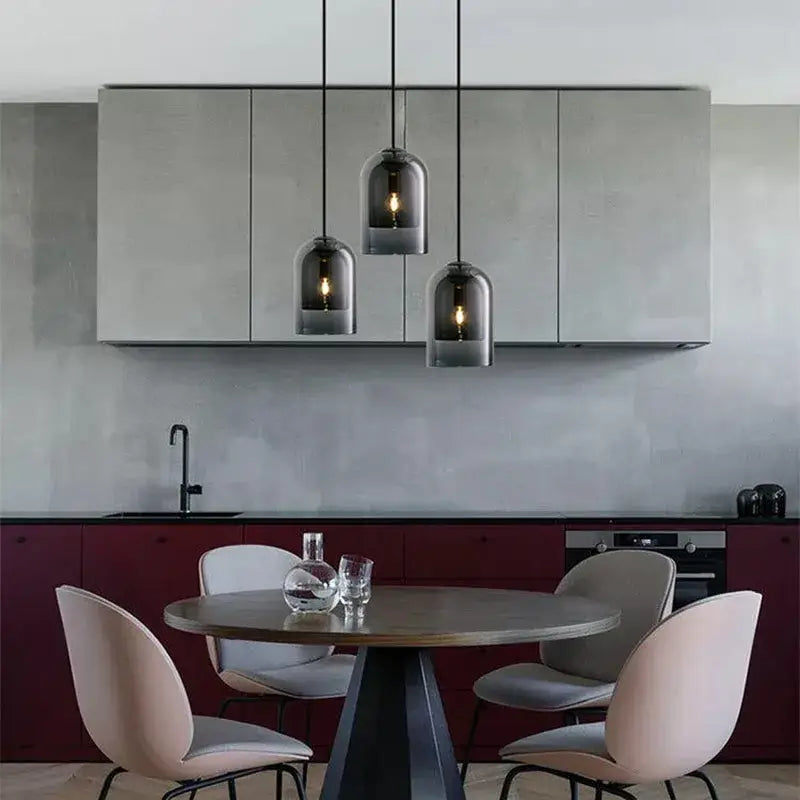 Three warm glowing glass led chandelier pendant lights suspended above a dining room table for elegant lighting