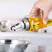 Clear glass seasoning dispenser bottle with stainless steel spout filled with golden olive oil for kitchen storage