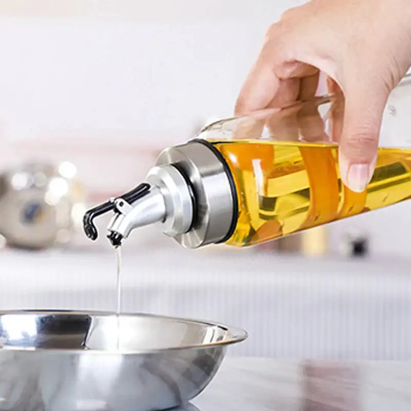 Clear glass seasoning dispenser bottle with stainless steel spout filled with golden olive oil for kitchen storage