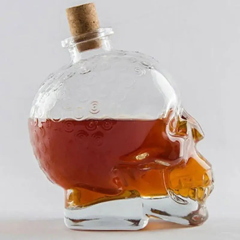 Clear glass skull bottle with cork stopper filled with amber liquid used as kitchen crystal wine and vodka decanter