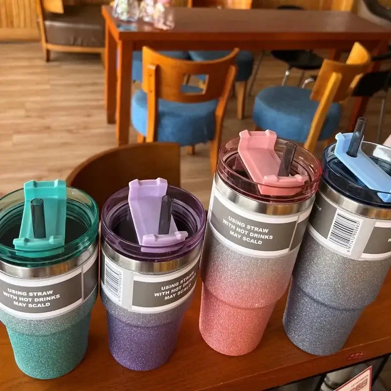 Four glittery double wall insulated stainless steel water bottles with colorful lids in teal purple pink orange and silver