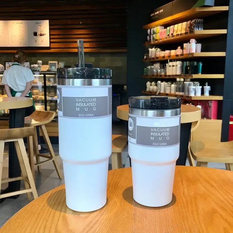 Two white double wall insulated stainless steel mugs with silver lids and gray labels in 30oz and 20oz sizes