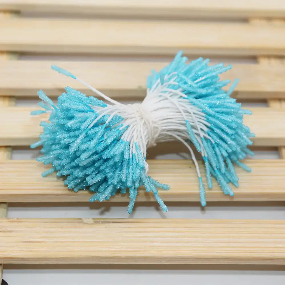 A bundle of turquoise and white glittery mini flower stamen craft picks with a fuzzy textured appearance for kids bedroom