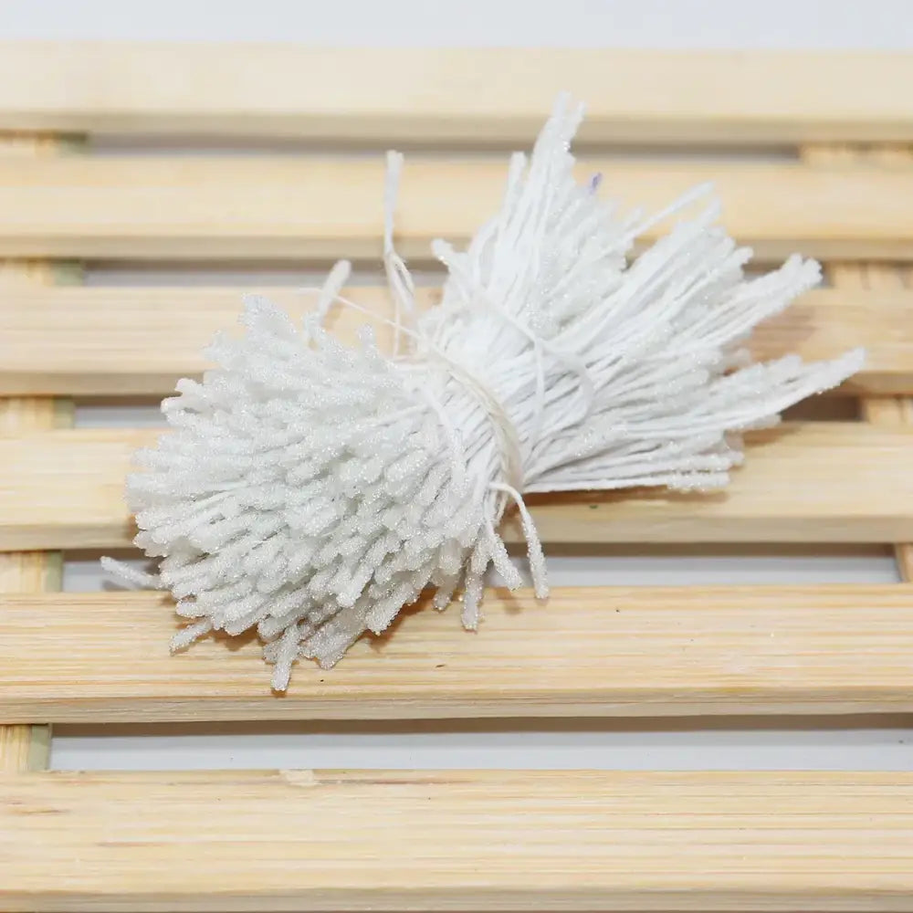 A bundle of white glitter pom pom mini flower stamen hair ties made of textured plastic for kids bedroom use