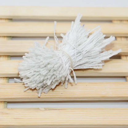 A bundle of white glitter pom pom mini flower stamen hair ties made of textured plastic for kids bedroom use