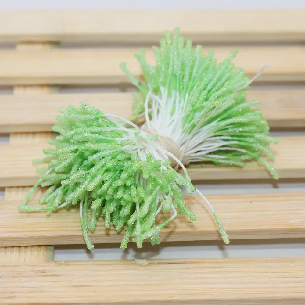 A bundle of artificial green glittery mini flower stamen sprouts with white stems tied together for kids bedroom hair ties