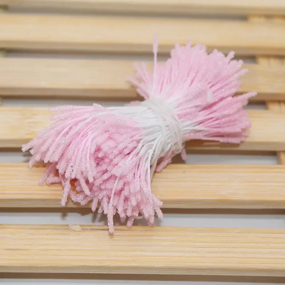 A bundle of pink and white glittery plastic mini flower stamen hair ties for kids bedroom use