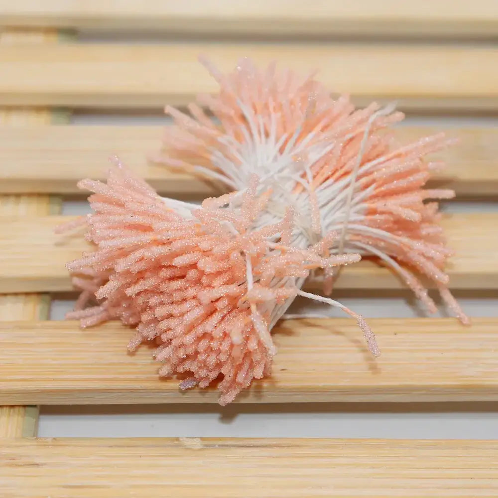 A cluster of peach-colored glittery artificial coral mini flower stamen hair ties with white stems for kids bedroom