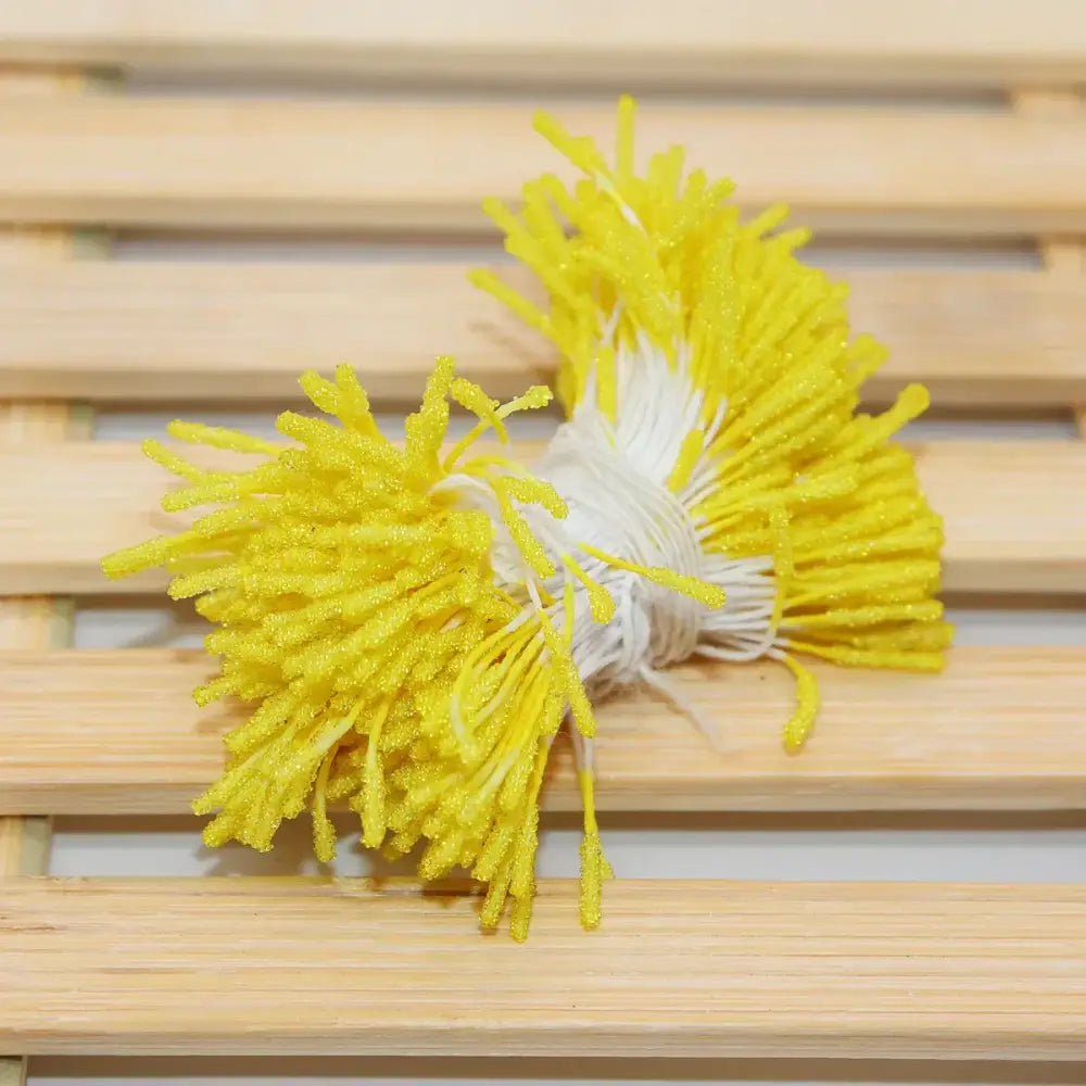 A cluster of bright yellow glittery plastic mini flower stamen picks with white stems for kids bedroom hair ties