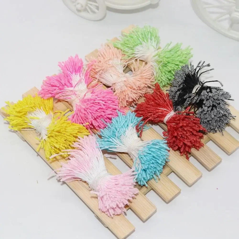 Colorful fluffy pom-pom tassels in pink yellow blue and red displayed as glitter mini flower stamen hair ties for kids