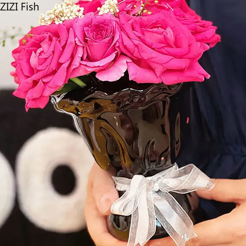 Glossy black ceramic decorbites ceramic vase with wavy rim and silver ribbon holding artificial flowers bouquet for bedroom decor