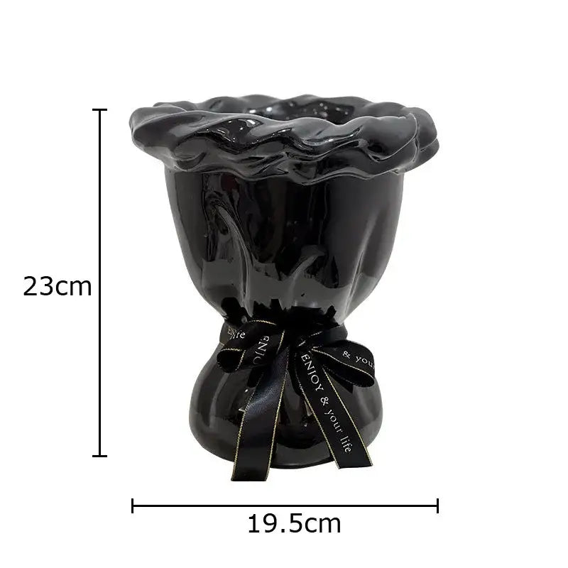Glossy black ceramic vase with ruffled rim and tied ribbon holding pink artificial flowers for bedroom decorbites decor