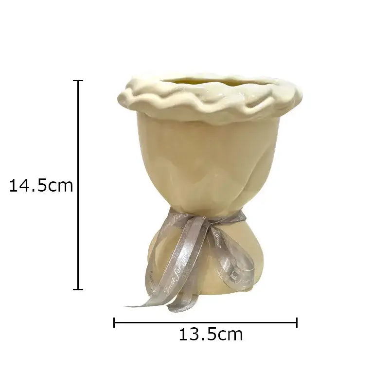 Cream-colored ceramic pie-shaped planter with silver ribbon complementing decorbites ceramic vase with artificial flowers bouquet