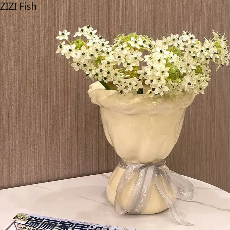 Cream-colored decorbites ceramic vase with ruffled rim and silver ribbon holding artificial flowers bouquet for bedroom decor