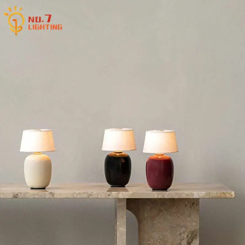 Three ceramics table lamps with glossy cream black and burgundy finish and white fabric shades for bedroom use