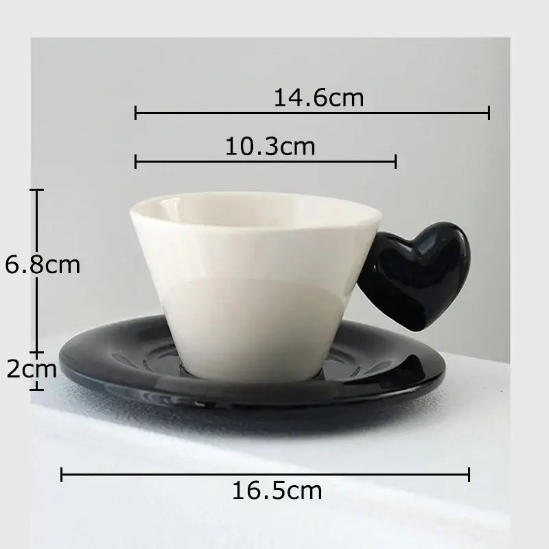A white porcelain lovers mug with a glossy black heart shape handle on a matching black saucer in dining room