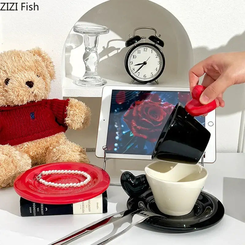 Glossy black heart shape porcelain lovers mug set with teacup and saucer being poured from a red silicone pitcher