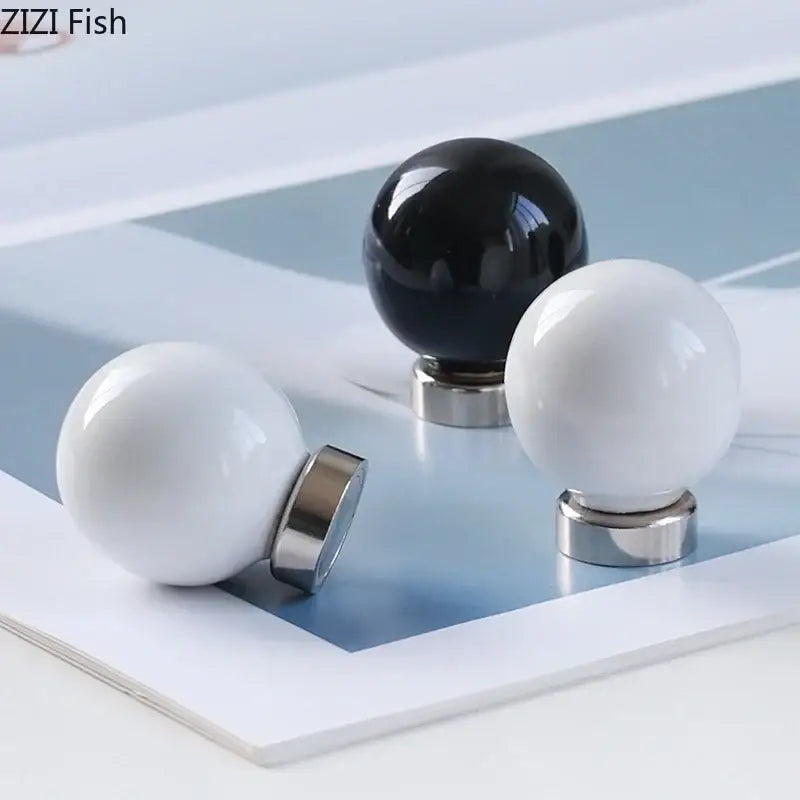 Glossy black and white ceramic wall hook clothing rack with polished spherical knobs on metallic bases