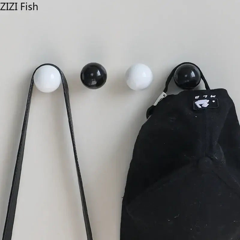 Set of four glossy black and white ceramic wall hooks with smooth finishes for a minimalist hook clothing rack