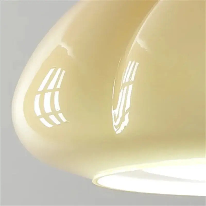 Glossy cream-colored ceramic pendant light with smooth curves and geometric cutouts for bedroom or restaurant balcony lighting